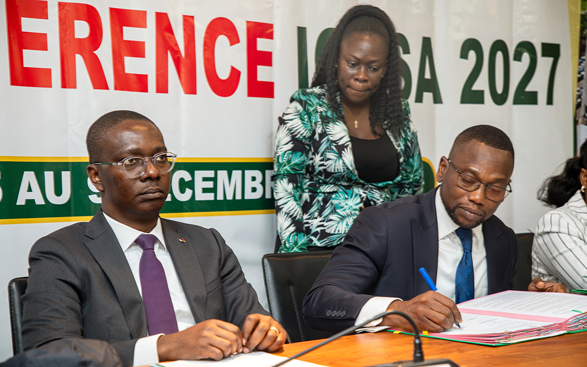 Prof. Benjamin Ignace Bodounrin Hounkpatin, Minister of Health, Benin with Monsieur Hugues Oscar Lokossou looking on - signing the MoU during the press conference.